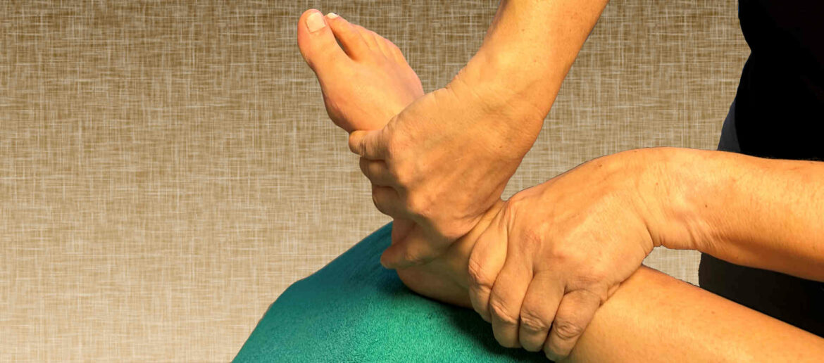 Therapeut behandelt ein Fußgelenk